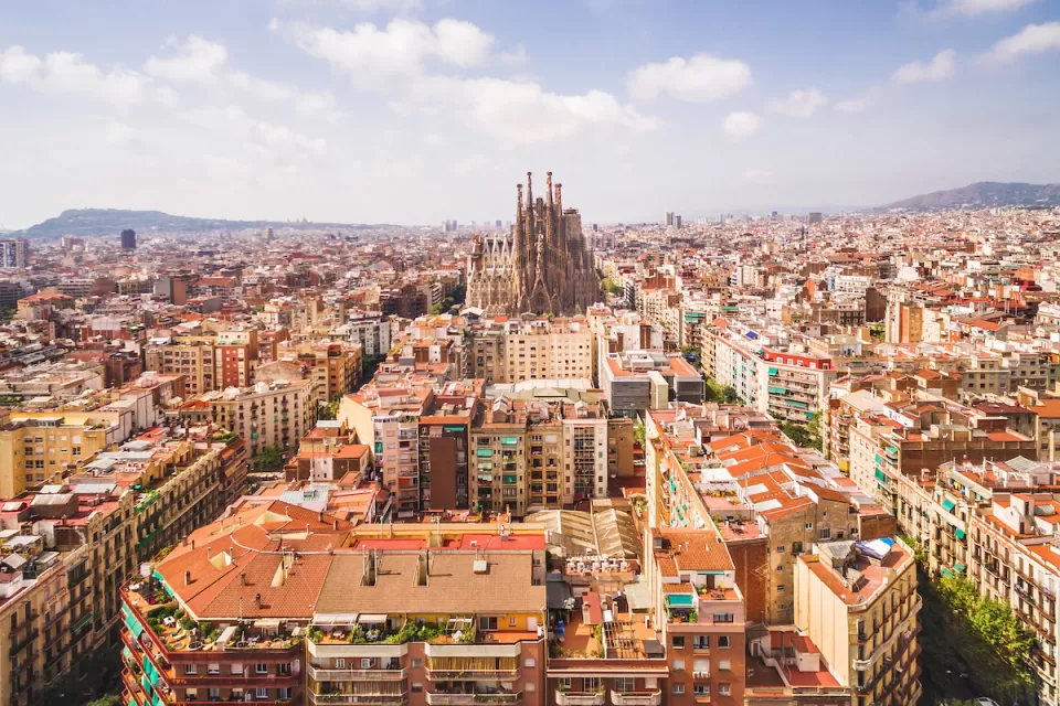 Aerial view of Barcelona, Spain with Sagrada Familia church in middle among dense buildings.